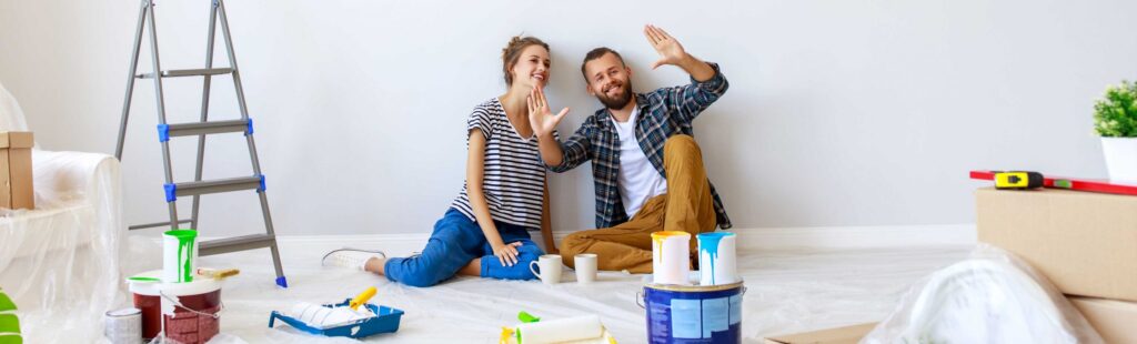Man and woman sitting on the floor of a room that they are in the process of renovating