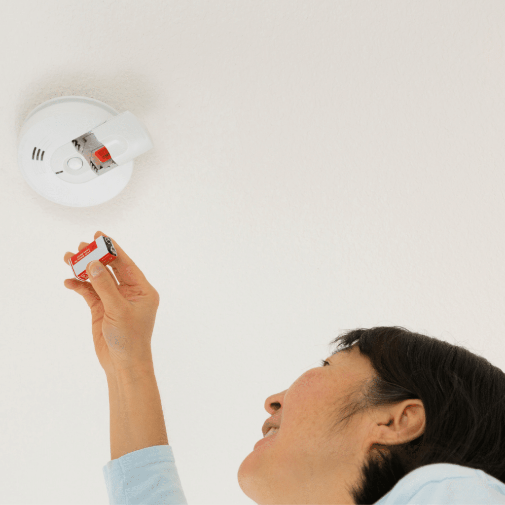 Woman changing the batteries of her carbon monoxide detector