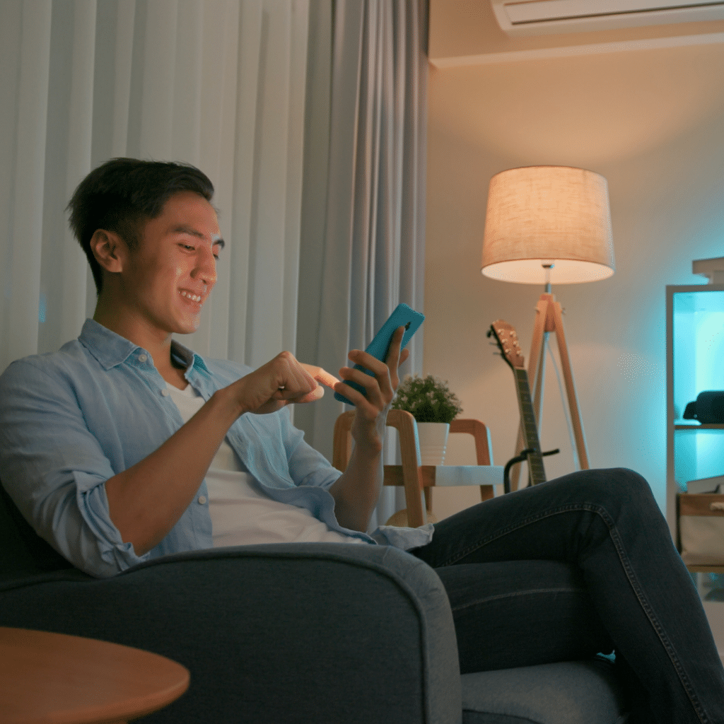 Man sitting on a couch happily using his smart phone