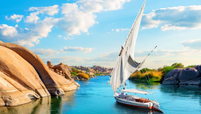Sailboat travelling down the Nile River with rocky mountains and nature in the background