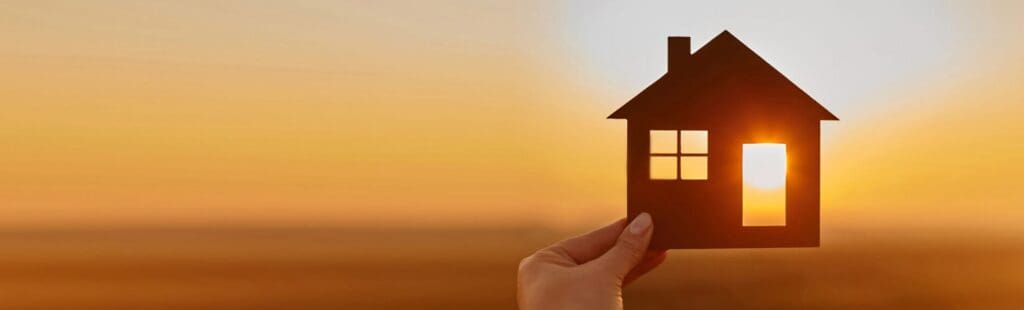 Cut out of a house being held directly in the sunlight with an orange sunset in the background