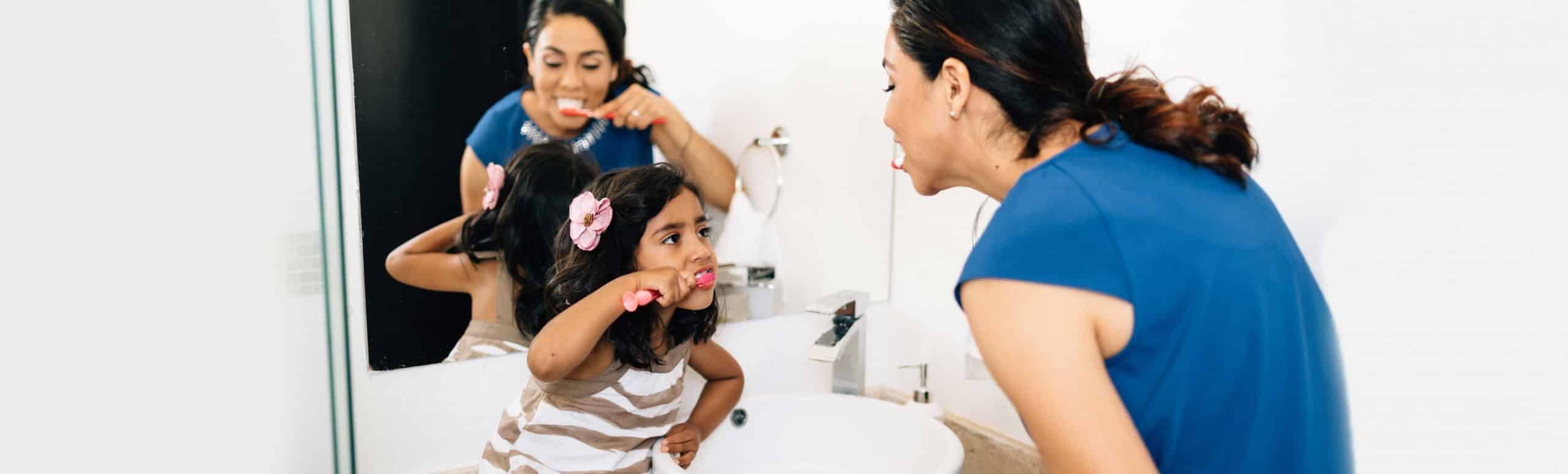 Mother and child brushing teeth together while saving water