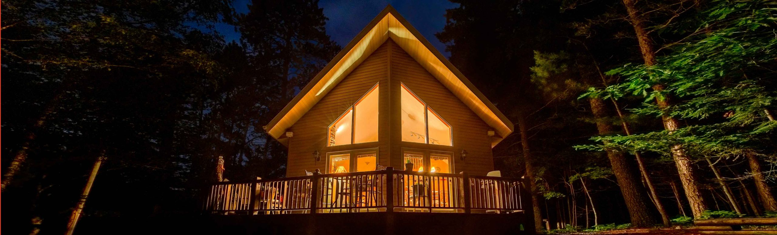 Bright lit up house in the middle of a forest during the night