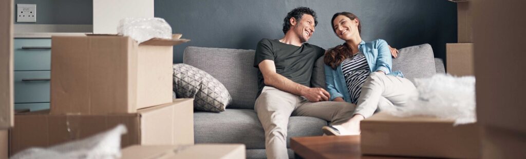 Couple sitting on a couch smiling and looking at each other