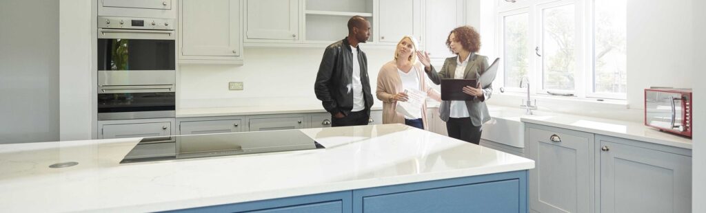 A realtor with two clients viewing the kitchen of a house