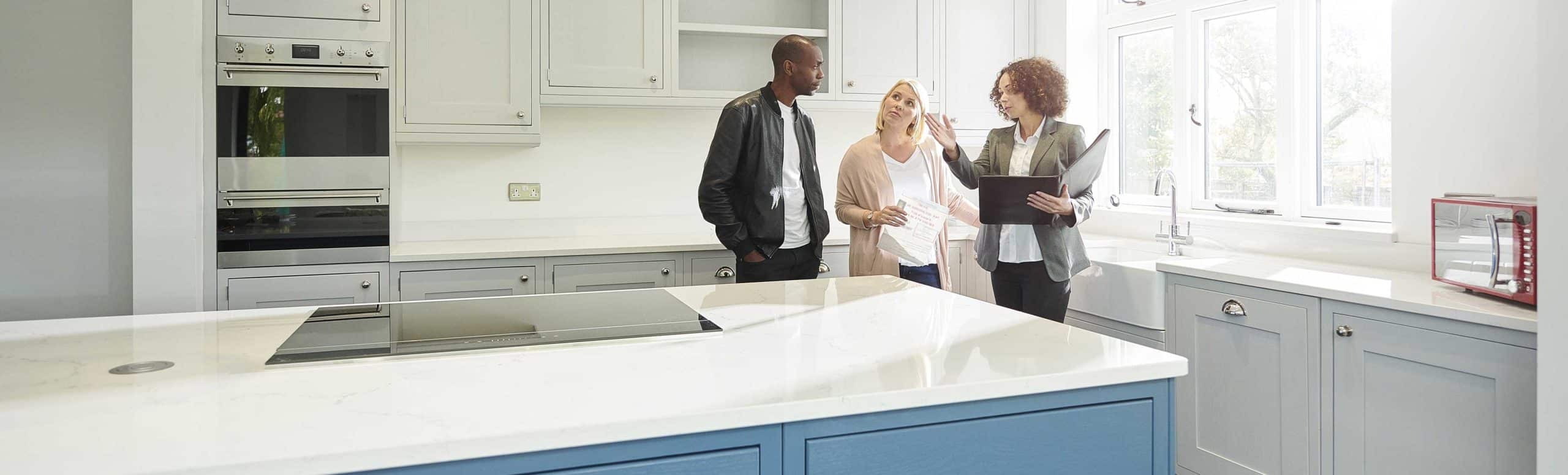 A realtor with two clients viewing the kitchen of a house