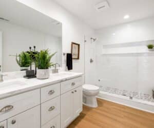 Open white coloured bathroom with dual sinks, a toilet, and shower