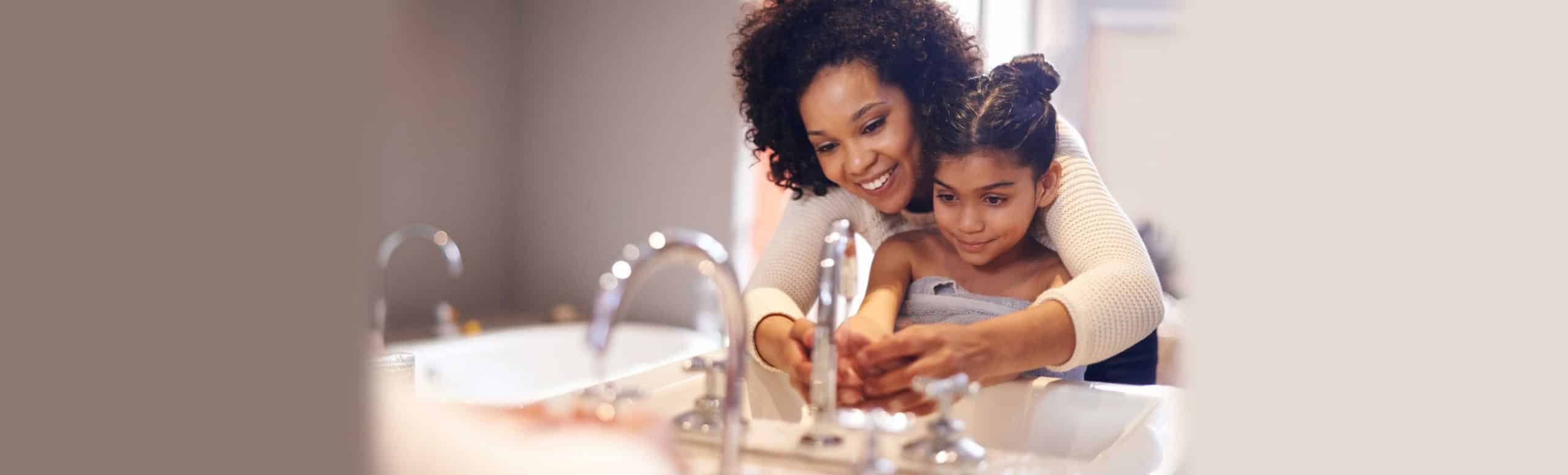 Mother and daughter washing hands together in a bathroom