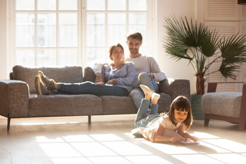 Couple sitting together on couch with a child laying on the ground