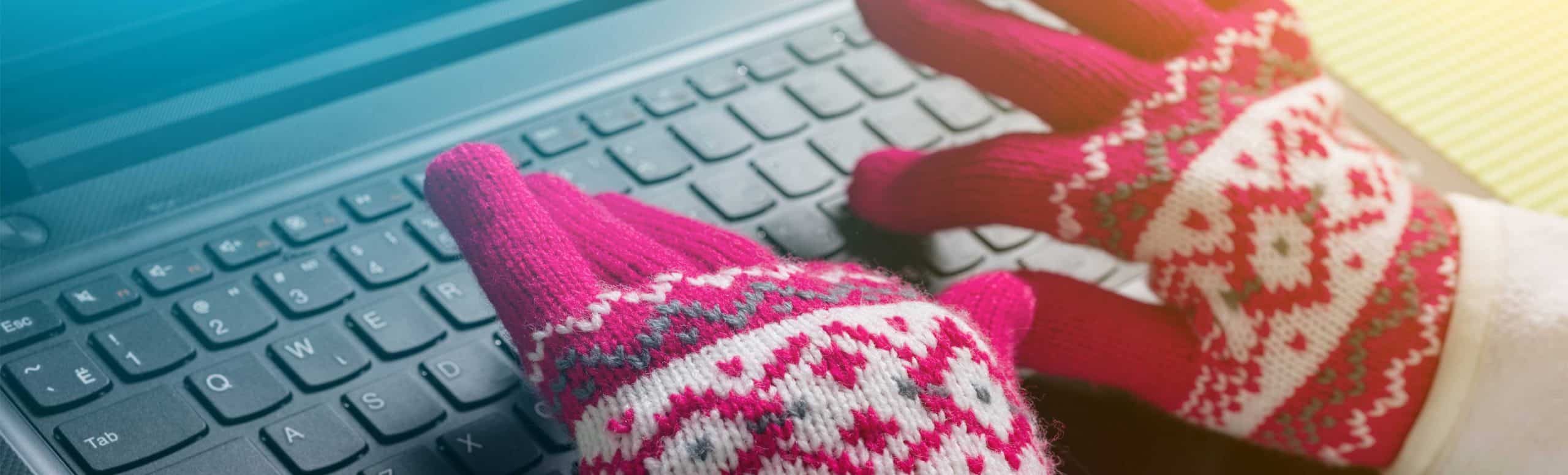 close up of a person wearing winter gloves and typing on a keyboard