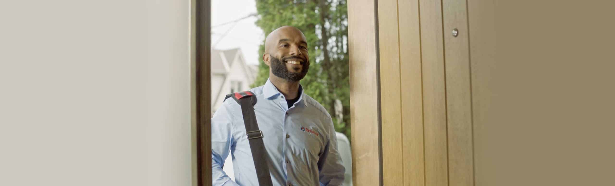 Male individual entering the front door of a house with a big smile