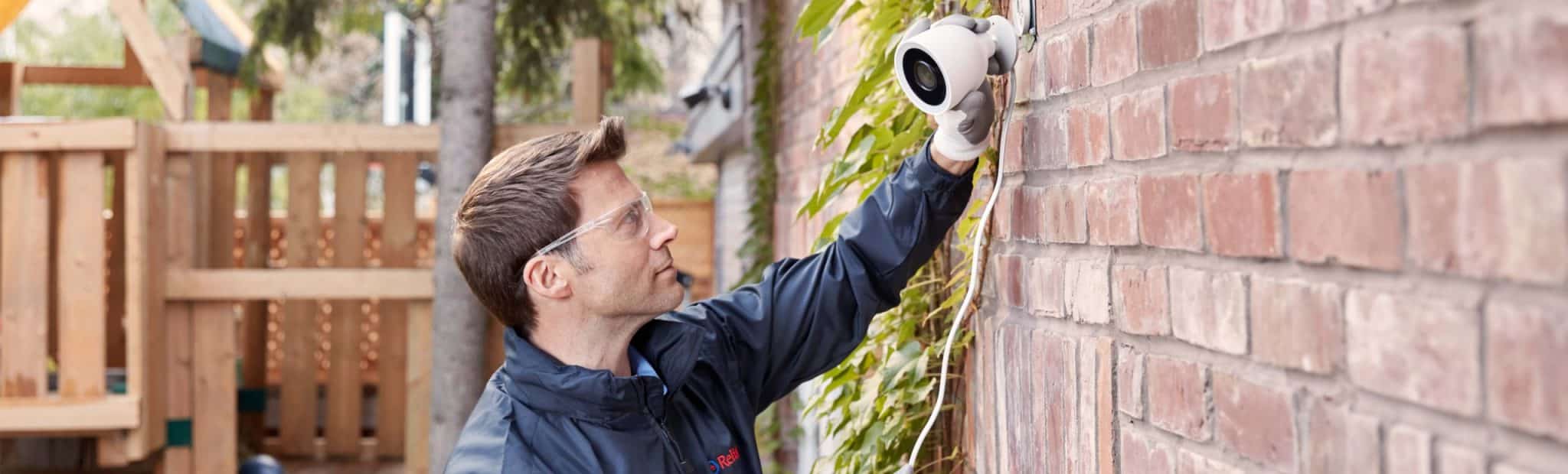 Reliance worker installing smart home camera outside of a house