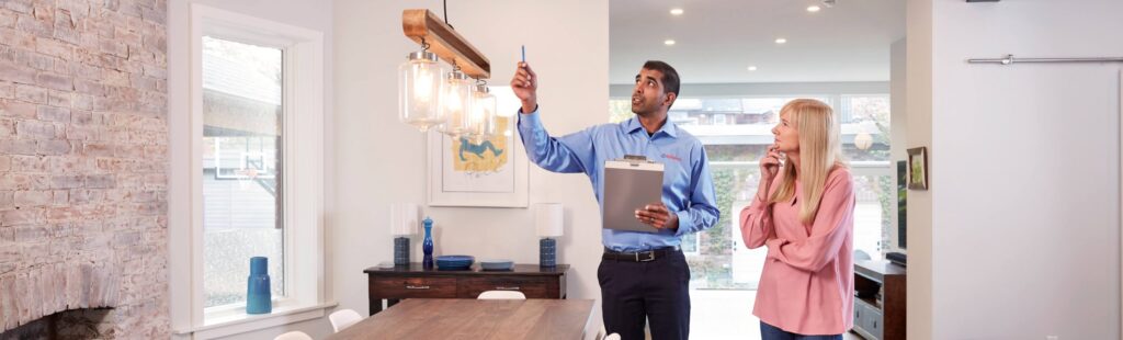 Male Reliance advisor pointing to electrical wire from lighting showing female customer
