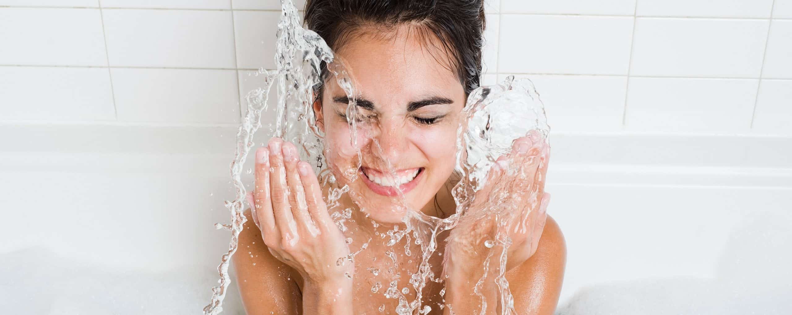 Woman in washroom Splashing water on face. Water Heater