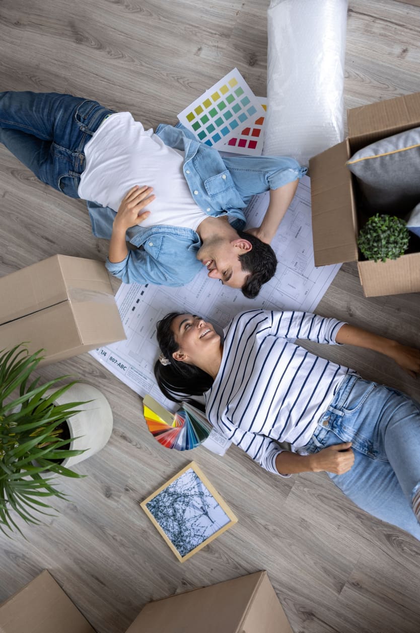 Happy Latin American couple having fun decorating their new house after moving in - lifestyle concepts