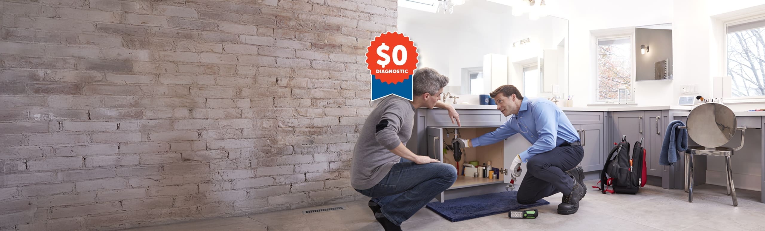 two plumbers kneeling and working under a sink