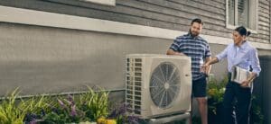 Heat pump outside of home with RHC technician and home owner