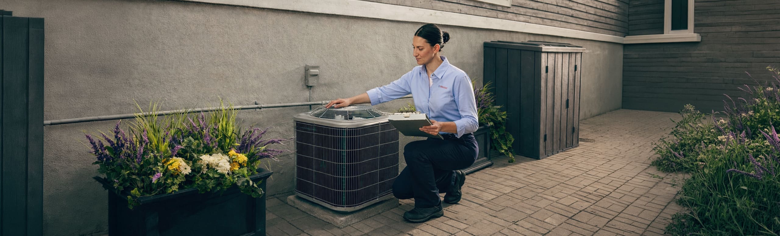 A female Reliance technician inspects an AC condenser outside a home